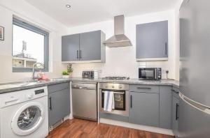 Una cocina con gabinetes grises y lavadora y secadora. en Big Ben 2 Bed, en Londres
