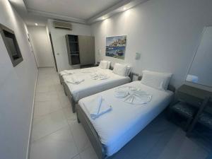two beds in a hotel room with white sheets at Oceanis Hotel in Karpathos