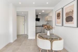 a dining room with a glass table and white chairs at Mar del Sur in Benalmádena
