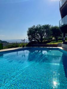 Una gran piscina azul con el océano al fondo. en The Green Nest - pool & lake view, en Costermano