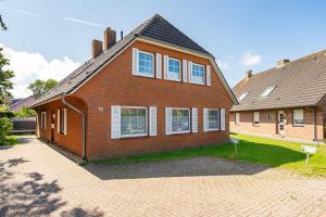 a red brick house with white windows on it at Knut in Greetsiel