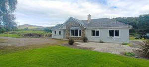 a white house with a green lawn at Tigh Dawros - Charming 4-bedroom house with WiFi in beautiful Kenmare, Kerry in Dinish Island