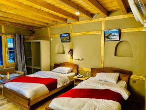 two beds in a room with wooden ceilings at Zimsa Resort Skardu in Skardu