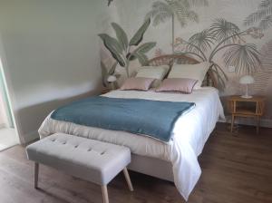 a bedroom with a large bed with a bench next to it at Le jardin d'Annie Chambres D'hôtes in Jaucourt