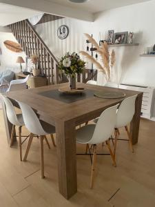 una sala da pranzo con un tavolo di legno e sedie bianche di Maison 4 chbs avec jacuzzi, au pied de la piste cyclable a Lacanau-Océan