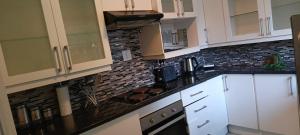 a kitchen with white cabinets and a black brick wall at 46 On Aries in Northwold