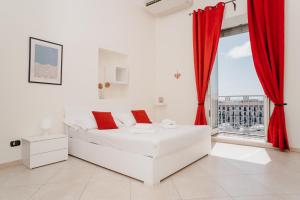 a white living room with red curtains and a white couch at Central Station by CasaNapoletana in Naples