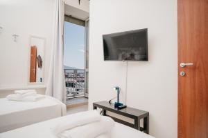 a hotel room with two beds and a tv on the wall at Central Station by CasaNapoletana in Naples
