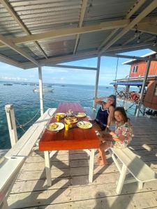 Pulau Mabul にあるMabuls Only Private Over-Water House Rentalの船のテーブルに座る男女