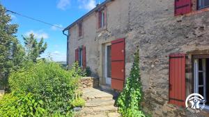 an old stone building with red doors and stairs at La lauziere in Assac