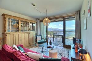 ein Wohnzimmer mit einem roten Sofa und einem großen Fenster in der Unterkunft ARC 1600, LE RIDGE, Appartement 08 personnes Vue Montagne - ski aux pieds - Sauna, Hammam, Piscine in Arc 1600