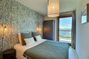 ein Schlafzimmer mit einem großen Bett mit einem großen Fenster in der Unterkunft ARC 1600, LE RIDGE, Appartement 08 personnes Vue Montagne - ski aux pieds - Sauna, Hammam, Piscine in Arc 1600 + 42 Fotos