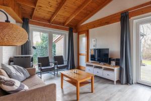 Una sala de estar con un sofá y un televisor. en Saskia, en Hollum