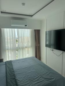 a bedroom with a bed and a flat screen tv at Empire Tower Suite - Luxe 1BR near the Beach in Jomtien Beach