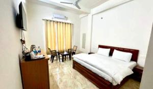 a bedroom with a bed and a table with chairs at Hotel O Prem Kunj in Faizābād