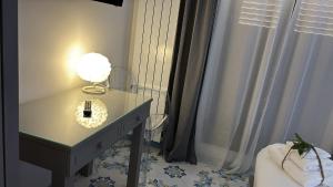 a table with a lamp on it next to a window at Ognissanti Rooms in Acireale