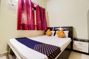 a bedroom with two beds and red curtains at Hotel O Nisarg Resort Satpati Beach in Satpati