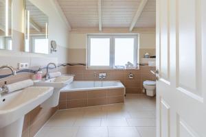 a bathroom with two sinks and a tub and a toilet at Ferienhaus - Sylt in Dagebüll +26 photos