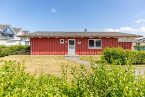 a red house with a white door in a yard at Ferienhaus - Sylt in Dagebüll