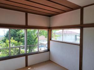 an empty room with three windows and a balcony at 大黒様ハウス in Hokuto