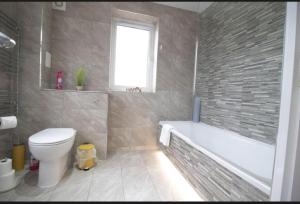 a bathroom with a tub and a toilet and a sink at Spacious contactor family Apartment in Swindon