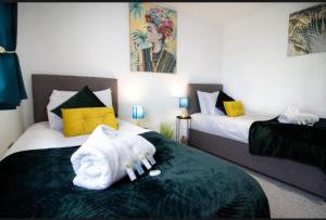 a bedroom with two beds with a towel on the bed at Spacious contactor family Apartment in Swindon