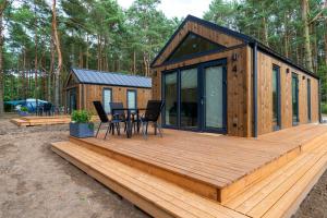 a wooden deck with a table and chairs on it at Domki letniskowe w Centrum Rekreacji i Wypoczynkou Deczno in Sulnówko +1 photo