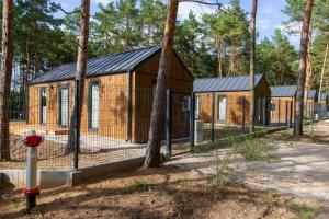 a row of small wooden houses in a forest at Domki letniskowe w Centrum Rekreacji i Wypoczynkou Deczno in Sulnówko