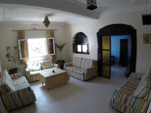 a living room with couches and a table and a window at Original Surf Morocco in Tamraght Ouzdar
