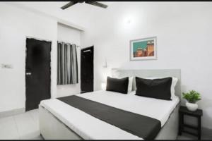 a white bedroom with a large white bed with black pillows at RROOMS Eco Hotel Silver Inn in Bareilly