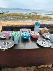 a table with plates and utensils on a table at the beach at Bunaken Coral Homestay in Bunaken