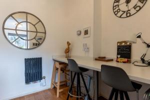 a room with a counter with chairs and a clock on the wall at ORME RISE - Beautiful first floor apartment in Llandudno