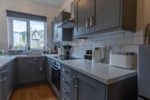 a kitchen with gray cabinets and a counter top at ORME RISE - Beautiful first floor apartment in Llandudno