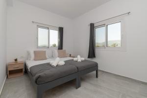 Una cama en una habitación blanca con dos ventanas. en Elhasa Laganas Villa BY "ELITE", en Laganas