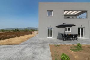 Casa blanca con mesa y sombrilla en Elhasa Laganas Villa BY "ELITE", en Laganas