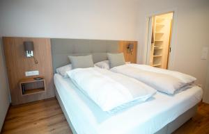 a large white bed with white sheets and pillows at OpenSky Wörthersee Lodge in Pörtschach am Wörthersee