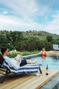 a man and woman sitting in lawn chairs by a swimming pool at Alojamentos Plansel - No Coração das Vinhas do Alentejo in Montemor-o-Novo