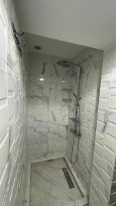a bathroom with a shower with white tiles at Duplex imiouaddar in Imi Ouaddar