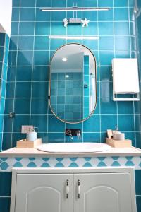 a blue tiled bathroom with a sink and a mirror at At Home - Luxury apartment Bari in Bari +18 photos