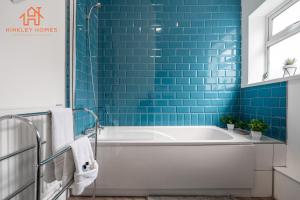 a bathroom with a tub and blue tiles at 9 Guests, 4 Bedrooms, Modern Comfort in Bootle in Litherland +20 photos