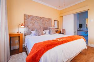 a bedroom with a large white bed with an orange blanket at 17onWellington Apartments in George +21 photos