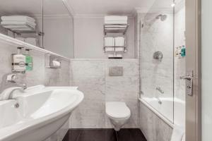 a bathroom with a toilet and a tub and a sink at Guild Hotel Marble Arch in London