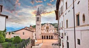 a church with a tower with a rainbow in the sky at Appartamento Lady in Spoleto