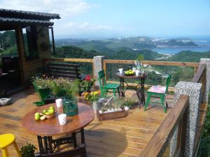 a deck with tables and chairs and a view of the ocean at Sunny Room in Jiufen