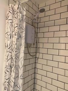 un bagno con tenda per la doccia e piastrelle bianche. di Hillside Launceston Cornwall a Launceston
