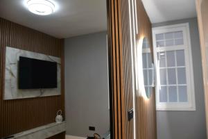 a room with a tv on the wall and a window at Nómada Orzán bajo in A Coruña