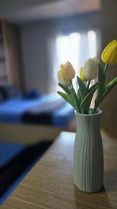 a white vase with flowers in it on a table at Studio With Citylights and SEAview near MALL inside IT PARK in Sampong