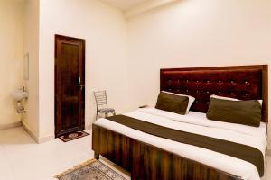 a bedroom with a large bed with a wooden headboard at Hotel O KAILASHA INN in Hasanganj