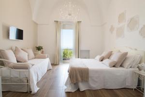 a white bedroom with two beds and a chandelier at Biancadamare in Ostuni