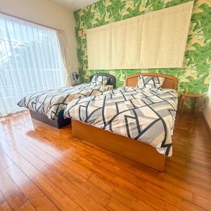two beds in a bedroom with green wallpaper at ペンション波 in Ufugumui